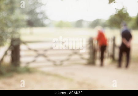 Zwei impressionistische Figuren zu durchlaufen ein Fußgängertor in einer Sommerlandschaft mit Bäumen Stockfoto