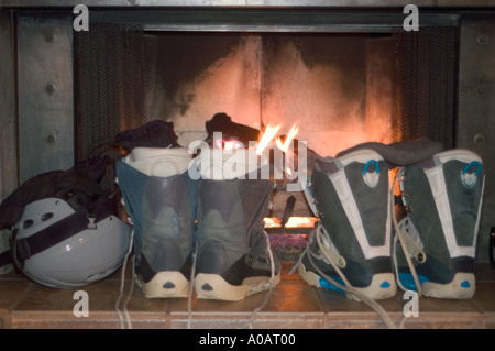 Eine horizontale Farbbild von Snowboardboots und einen Helm vor einem Feuer trocknen Stockfoto