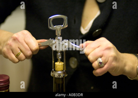 Frau Kork aus Weinflasche mit einem Korkenzieher entfernen. St Paul Minnesota MN USA Stockfoto