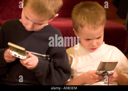 Zwei jungen Alter von 5 und 7 intensiv spielen ihre Game Boys. St Paul Minnesota MN USA Stockfoto