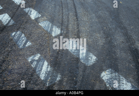 Weiße strichpunktiert Vorfahrt auf grauen Asphalt Straße fast ausgelöscht von schwarzem Kautschuk Reifen Bremsspuren Stockfoto