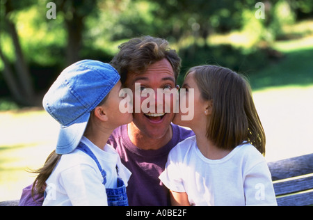 Zwei junge Mädchen ihren Vater auf die Wange küssen Stockfoto