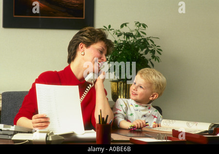 Arbeitende Mutter im Büro sowohl am Telefon sprechen und reagiert ihr Kind gleichzeitig jonglieren Stockfoto