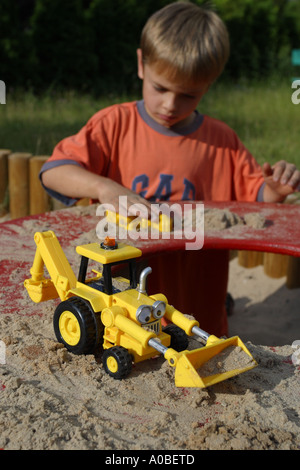 Jungen spielen im Sandkasten mit Spielzeug Bagger Stockfoto