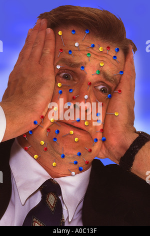 Mann mit Kopfschmerzen und Pins im Gesicht Stockfoto