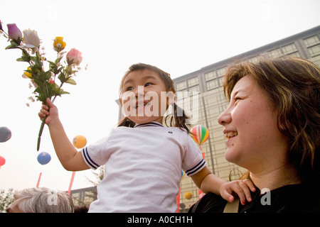 Ein chinesisches Mädchen hält eine Reihe von Blume mit ihrer Mutter in Peking China Stockfoto