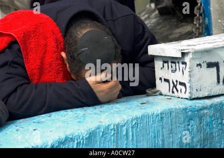 Israel oberen Galiläa Safed Alter Friedhof Nahaufnahme von einem Mann Prosternating auf einem alten blau bemalten Grab Stockfoto