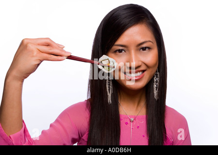 Orientalische Frau vietnamesische Amerikaner in traditionelle vietnamesische Kleid mit Sushi auf Chop sticks lächelnd Stockfoto