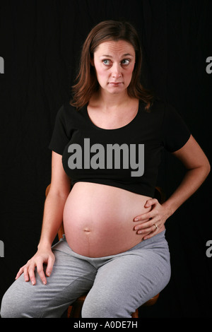 Hochschwangere junge Frau beruht einerseits auf exponierten Beule Magen ungeborenen Fötus mit betroffenen Gesichtsausdruck Stockfoto