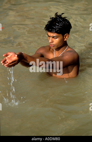 Indischer junge Mann Baden und beten in den heiligen Fluss Ganges neben einem Varanasi Ghat Hinduismus Uttar Pradesh, Indien Stockfoto
