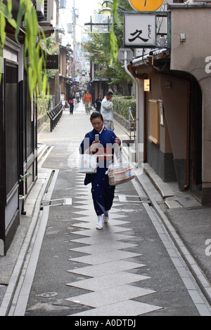 Eine Japanerin im traditionellen Kimono überprüft ihr Handy für SMS-Nachrichten in der Ponto Cho Bezirk von Kyoto Stockfoto