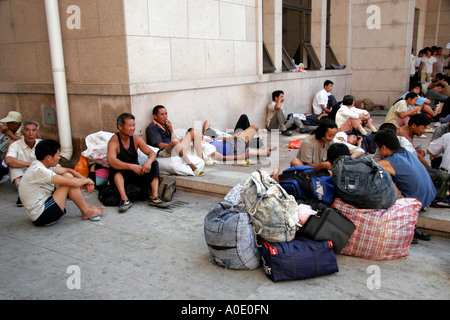 Chinesische Arbeiter warten auf Züge außerhalb Beijing Railway Station. Stockfoto