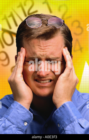Geschäftsmann mit Kopfschmerzen vor Uhr Stockfoto