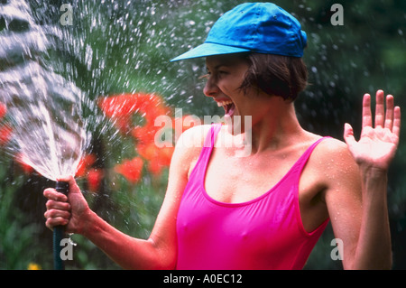 Frau im Freien mit Gartenschlauch Stockfoto