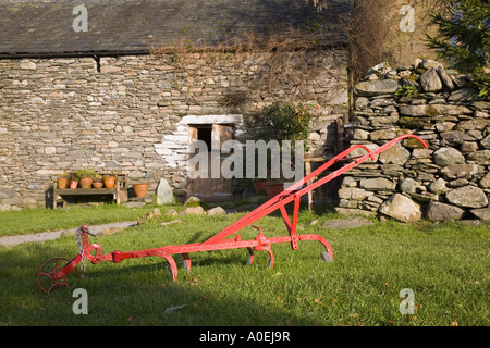 Alte rote Hand Pflug Artefakt außerhalb der traditionellen Scheune mit Stalltür in "Lake District" Nationalpark Watendlath Cumbria Stockfoto