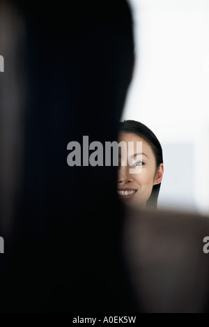 Womans zurück mit ihrem lächelnden Reflexion im Spiegel Stockfoto