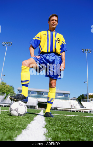 Porträt von Profi-Fußballer in einheitlichen posiert mit Ball auf Feld Stockfoto