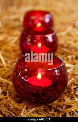 Drei Teelichter Flackern in Folge auf Bett aus Stroh Stockfoto