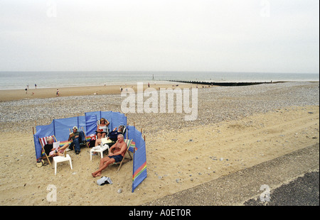 Eine Familie Tierheime vor dem Wind am Strand von Cromer UK Stockfoto