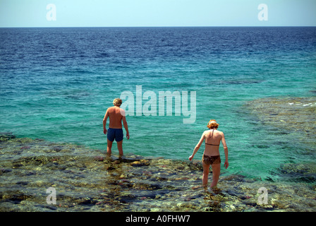 Youngmale und weibliche Touristen zu Fuß vorsichtig auf Felsen am Roten Meer in Naama Bay Sharm El Sheikh Ägypten Stockfoto