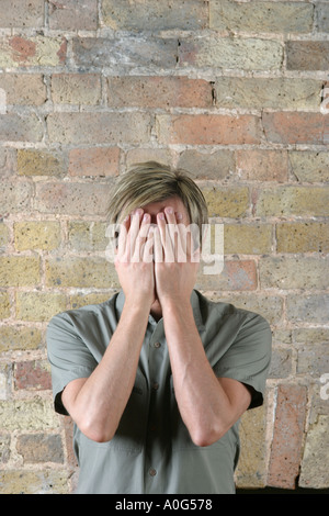 Junger Mann mit seinem Gesicht in seinen Händen Stockfoto