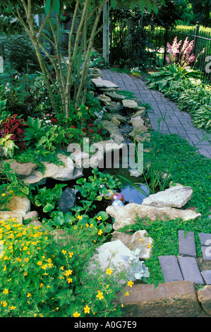 Kleine dekorative Fische Pool mit Springbrunnen Wasserfall im Landschaftsgarten mit Backstein Wege und Terrasse, Midwest USA Stockfoto