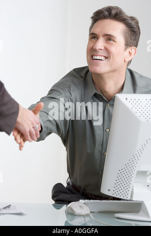 Geschäftsmann am Schreibtisch Händeschütteln Stockfoto