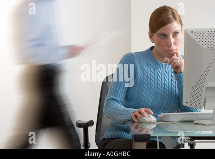 Frau am Computer mit Person übergeben Stockfoto