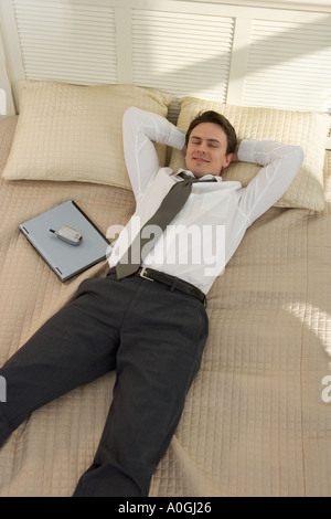 Geschäftsmann auf Bett liegend mit laptop Stockfoto