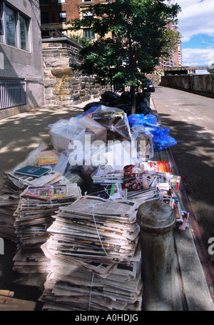 Gebundene alte Zeitungen und Plastikmüllbeutel warten auf Abholung und Recycling durch die Sanitärabteilung in New York City Stockfoto