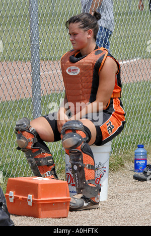 Weibliche Teenager Hauptliga Softball Spieler sitzen auf der Bank tragen die Catcher Schutz Weste und Knie-pads Stockfoto