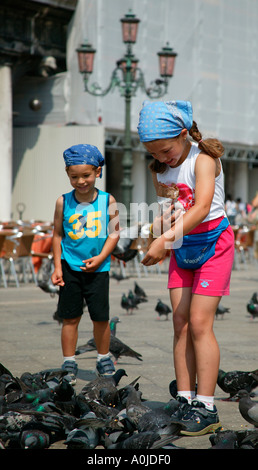 Kinder in Piazza San Marco Venice Italien Tauben füttern Stockfoto