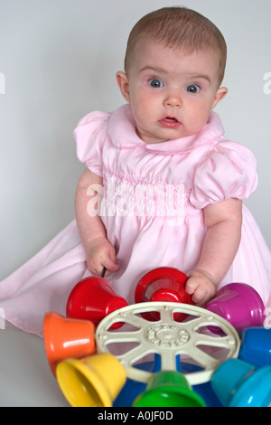 Baby Girl Überraschung zeigt, wie sie mit musikalischen, Spielzeug Glocken zum ersten Mal spielt. Stockfoto