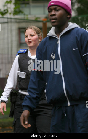 Ein junger Afro-karibischen Teenager & weibliche Gemeinschaft Polizist während eines Spiels der Fußball auf eine Wohnsiedlung. Stockfoto