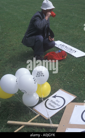 Eine ältere Demonstrant hält um ein Getränk aus seiner Flasche während einer Demonstration gegen Krankenhaus-Verschlüsse haben. Stockfoto