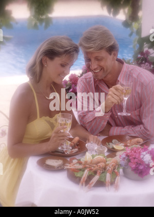jung, Ehepaar mittleren Alters, die romantischen Mahlzeit im Abendlicht auf der Terrasse am pool Stockfoto