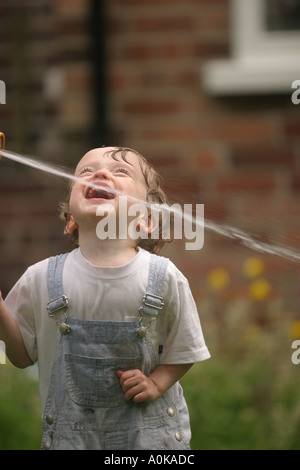 Lewis im Alter von zwei spielen mit dem Gartenschlauch in der GardenLewis im Alter von zwei spielen mit dem Gartenschlauch im Garten Stockfoto