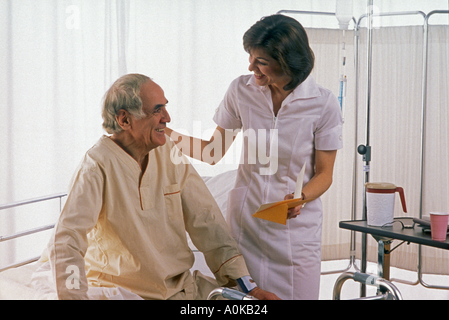 Krankenschwester bekommen gut Karte zu lesen, zu einer sich erholenden Patient sitzt am Krankenhausbett Stockfoto