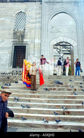 Mann, die türkische Flagge vor, Eingang Torbogen und Tauben auf den Stufen, Yeni Camii, neue Moschee, Istanbul, Türkei zu verkaufen. DSC 7141 Stockfoto