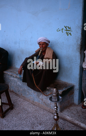 Ein ägyptischer Mann raucht eine Wasserpfeife in einem Café im Dorf Gesirat Elbaraat, am Westufer des Nils in Luxor, Ägypten Stockfoto