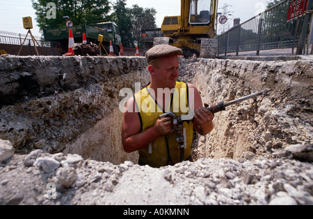 Ein Mann gräbt ein Loch in der Straße in London UK Stockfoto