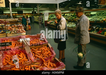 Ein Mann und eine Frau betrachten Karotten im Bereich Obst und Gemüse in einem ASDA Supermarkt in Dewsbury, Yorkshire, England Stockfoto