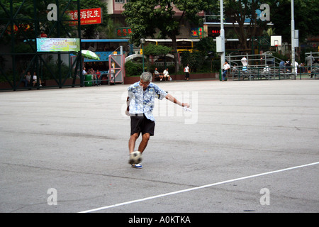 aktive ältere Mann kickt einen Fußball im Southorn Park, Wanchai, Hong Kong SAR Stockfoto