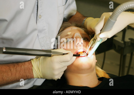Zähne und Zahnfleisch Behandlung durch einen Zahnarzt und seine Assistentin an einem Patienten in einem Zahnarzt-Stuhl in einer Zahnarztpraxis Stockfoto