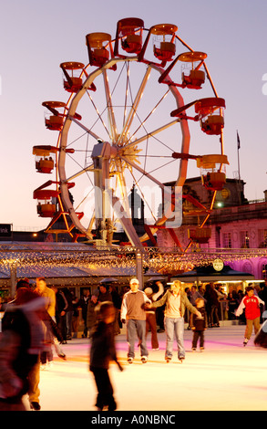 Winter-Wunderland Veranstaltung außerhalb Cardiff City Hall Wales UK mit Menschen Schlittschuhlaufen auf der Eislaufbahn und Riesenrad im Hintergrund Stockfoto