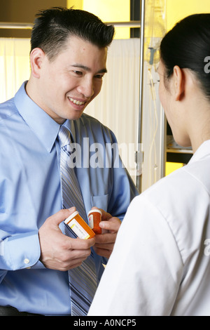 Asiatische männlicher Patient erhält Medikamente von Ärztin. Stockfoto