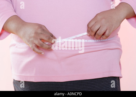 Schwere Frau misst ihre Taille mit einem Maßband. Stockfoto