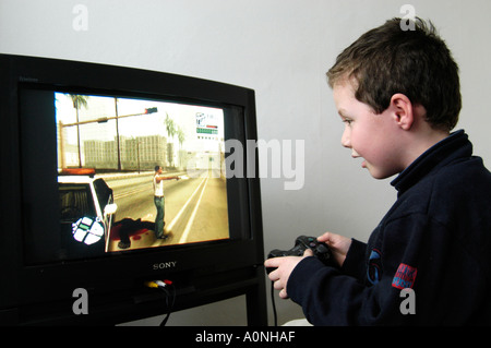 Kleine Jungen spielen gewalttätige 18 Zertifikat bewertet Computerspiel Grand Theft Auto auf Sony Playstation Konsole, England, UK Stockfoto