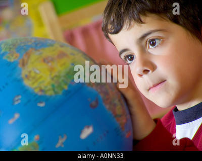 Schließen Sie die Ansicht auf Kleinkinder jungen in der Schule Kindergarten Klasse Blick auf Atlas Weltkugel Stockfoto