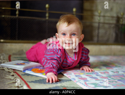 Lächelndes Baby krabbelt zu Hause auf Spielmatte mit Bilderbuch, zeigt frühkindliche Entwicklung und Familienleben. Stockfoto